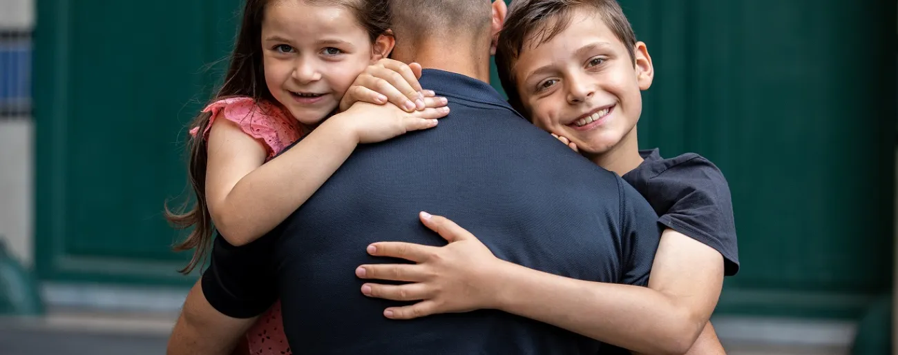 Pompier et enfants s'enlaçent