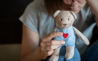 enfant tenant une peluche avec un broder sur le torse