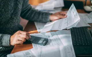 Personne calculant sont budget au milieu de factures et avec une calculatrice
