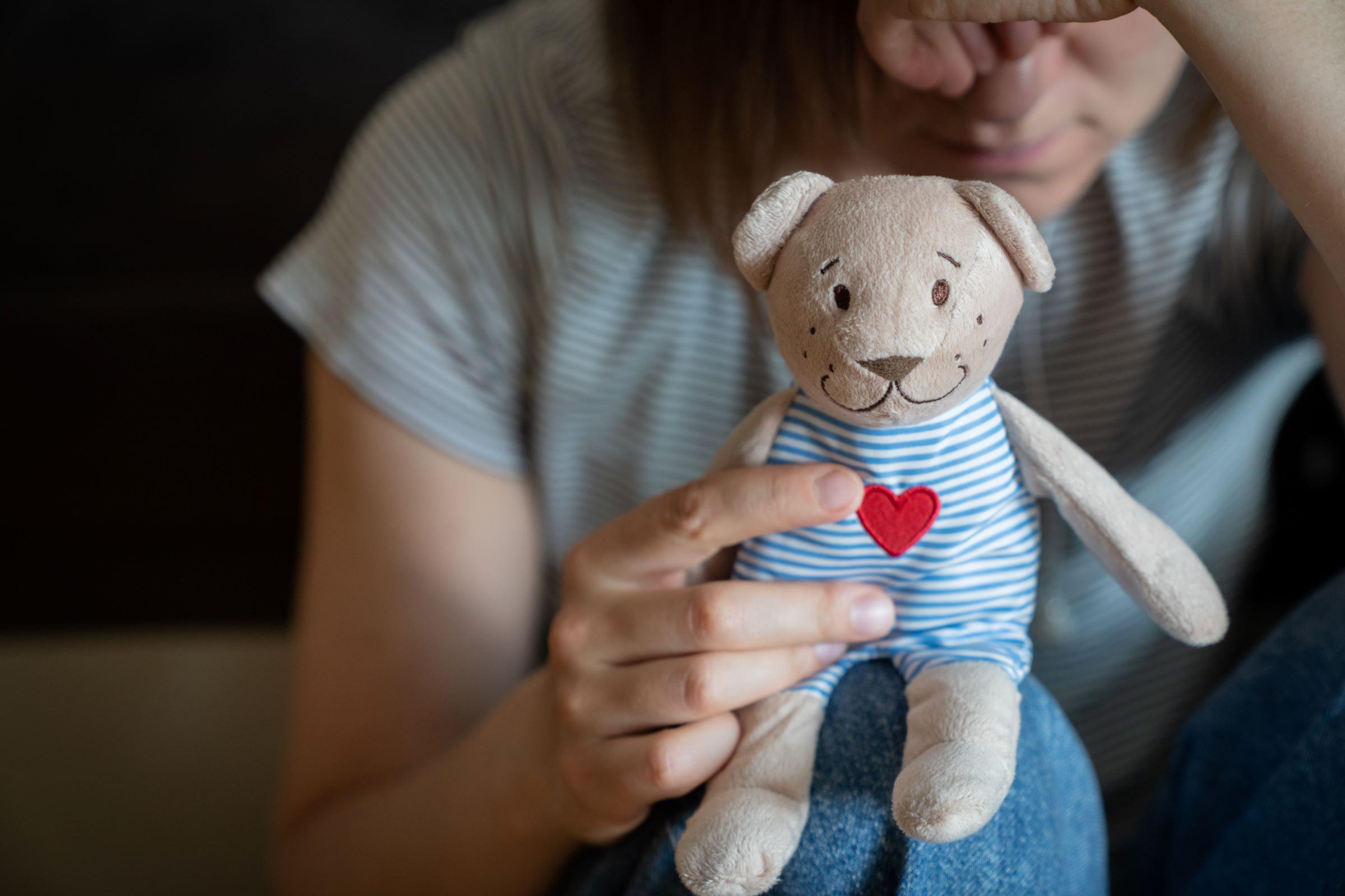 enfant tenant une peluche avec un broder sur le torse
