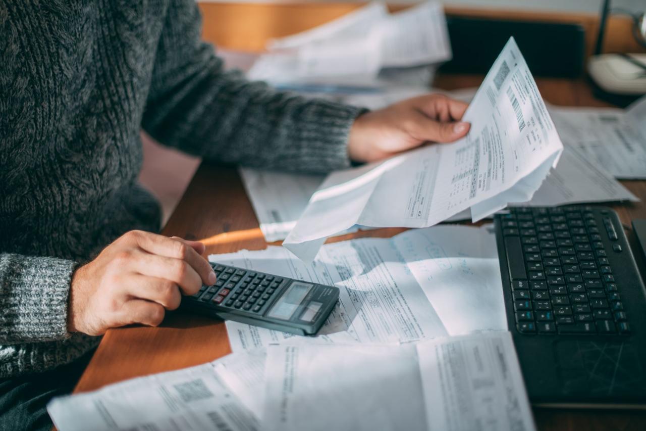 Personne calculant sont budget au milieu de factures et avec une calculatrice