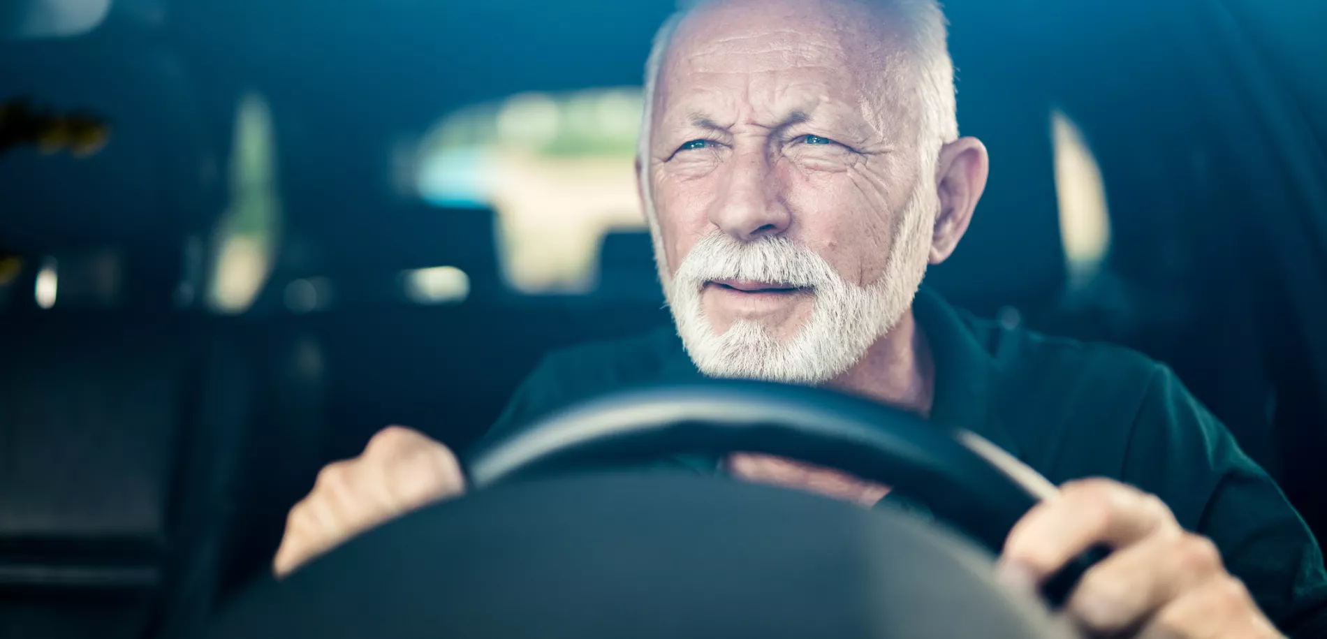 Homme aîné ayant la mauvaise vue d'oeil et faisant l'effort pour voir la route