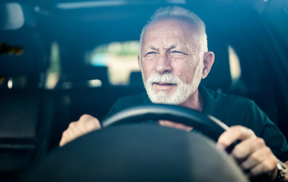 Homme aîné ayant la mauvaise vue d'oeil et faisant l'effort pour voir la route